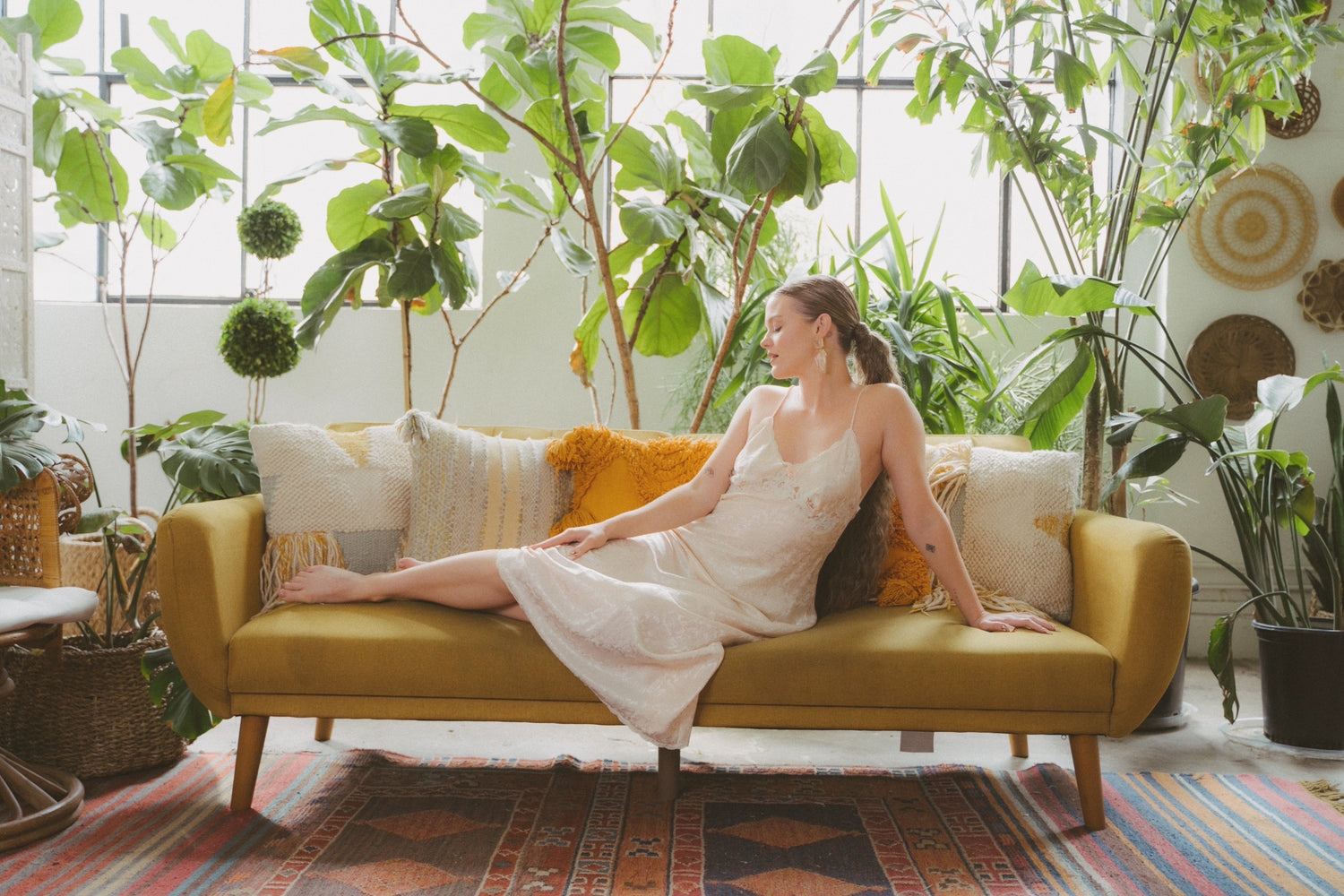 Faith Richards reclining on a couch surrounded by plants